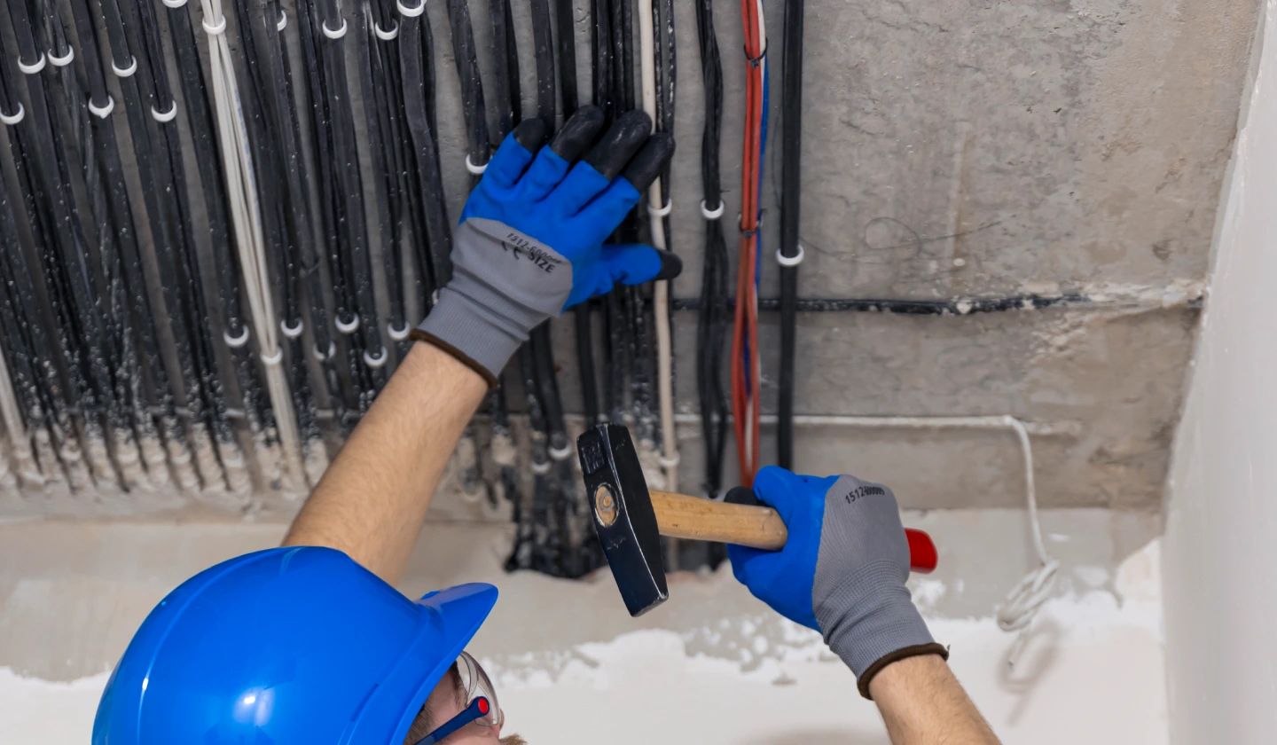 Electricista tendiendo cables eléctricos por una canalización en el techo de una vivienda