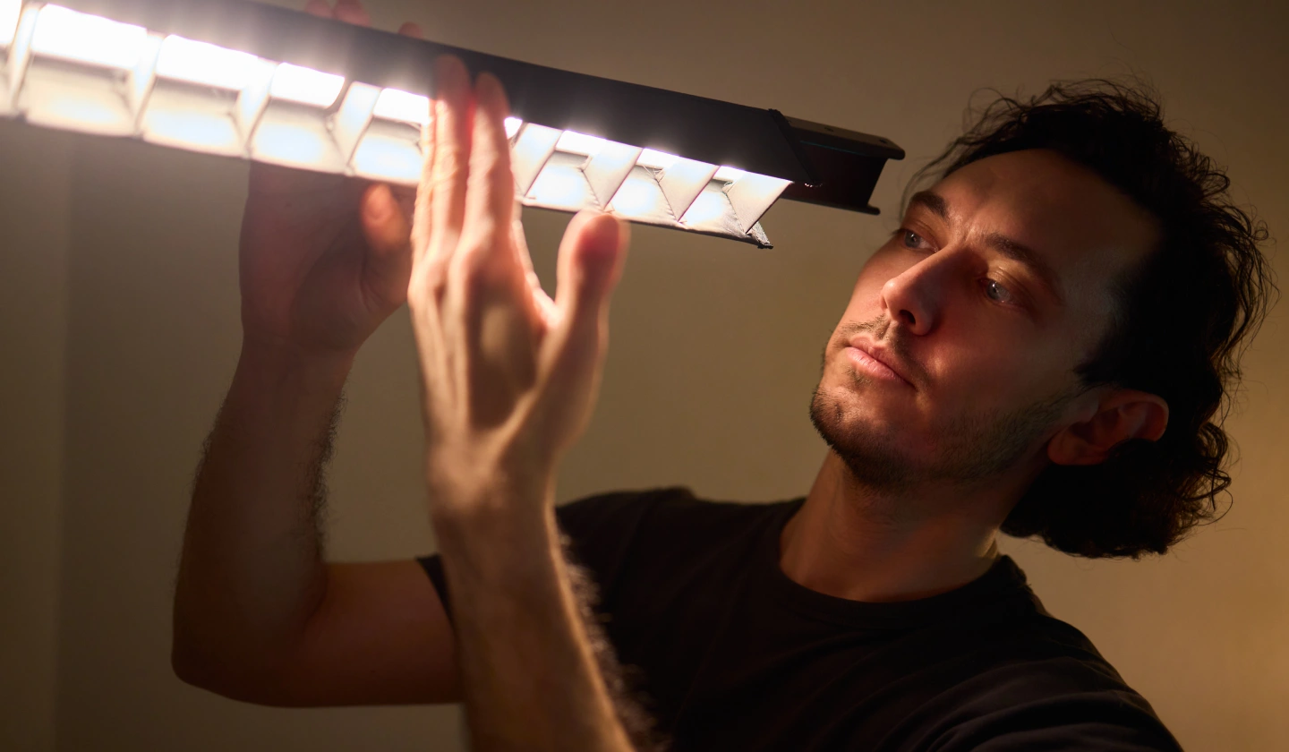 Técnico ajustando una luminaria lineal encendida con difusor de lamas