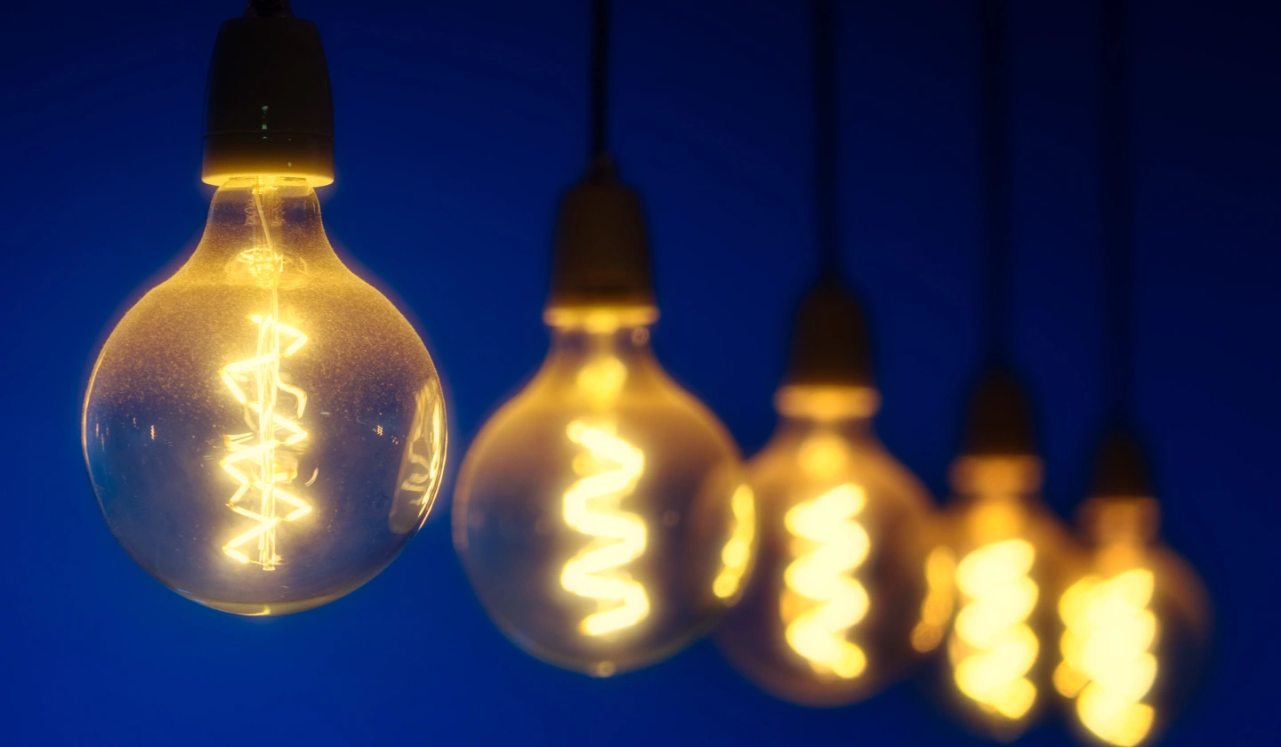 Bombillas de filamento con luz cálida colgadas sobre un fondo azul