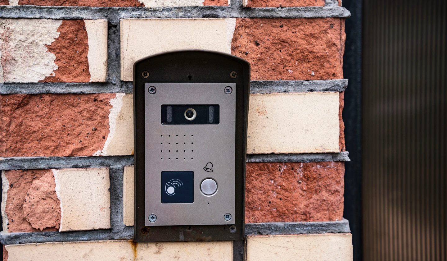 Placa de calle de videoportero con cámara instalada en un muro de ladrillo