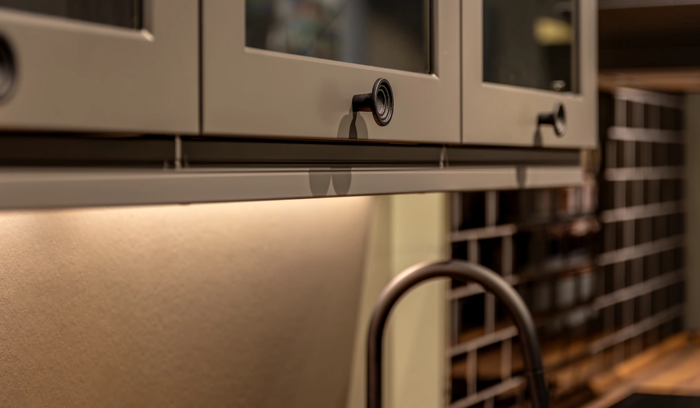 Tira LED instalada bajo los muebles altos de una cocina que ilumina la encimera sin sombras