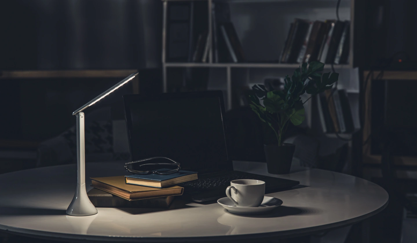 Flexo LED que proyecta un círculo de luz sobre una mesa en una habitación en penumbra