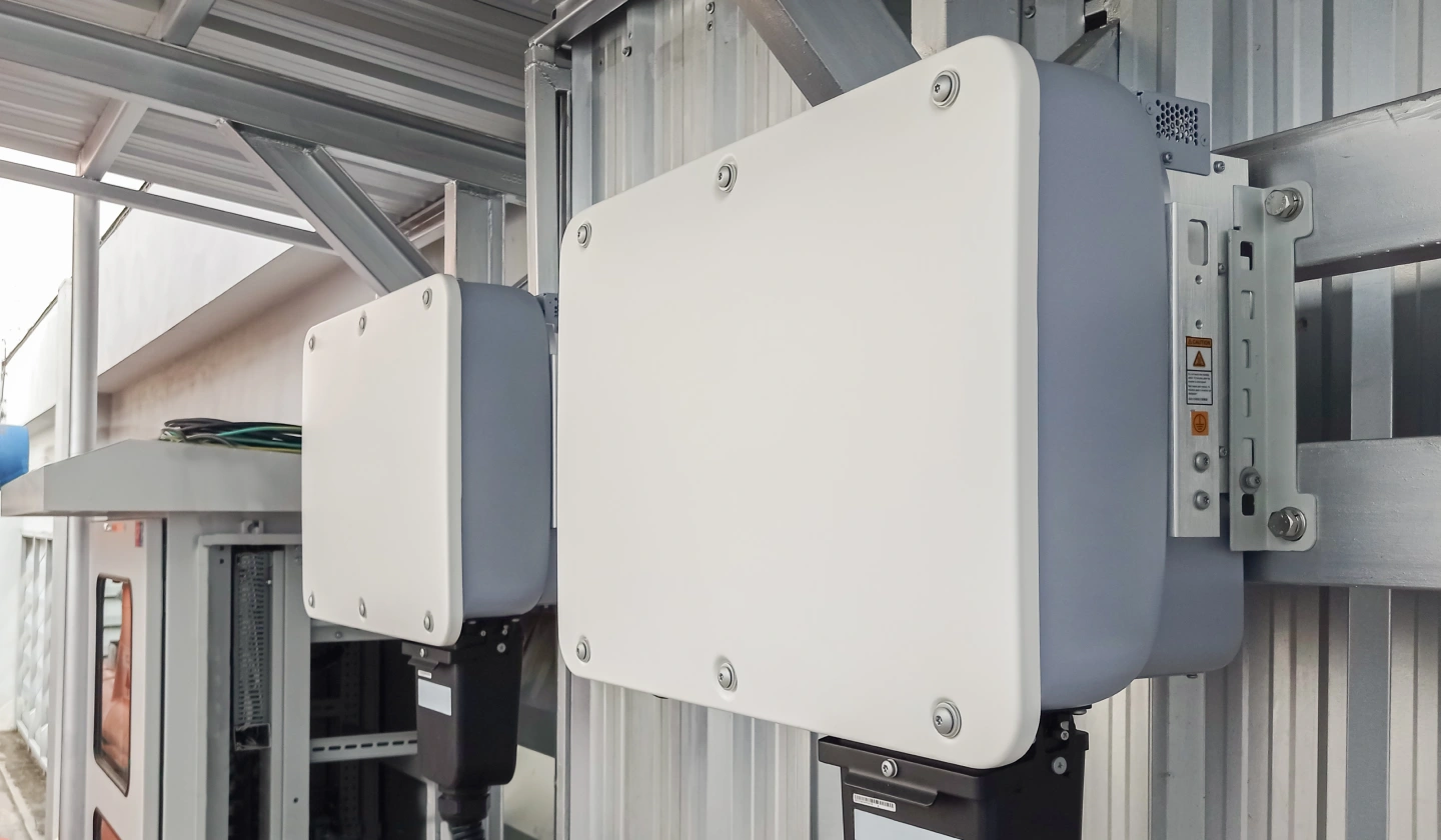 Dos inversores solares montados sobre una pared de chapa en una instalación fotovoltaica